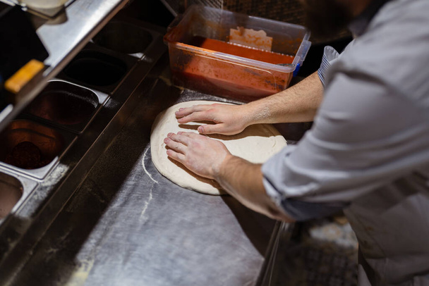 Erkek aşçı elleri pizzacı mutfağında pizza yapıyor. - Fotoğraf, Görsel