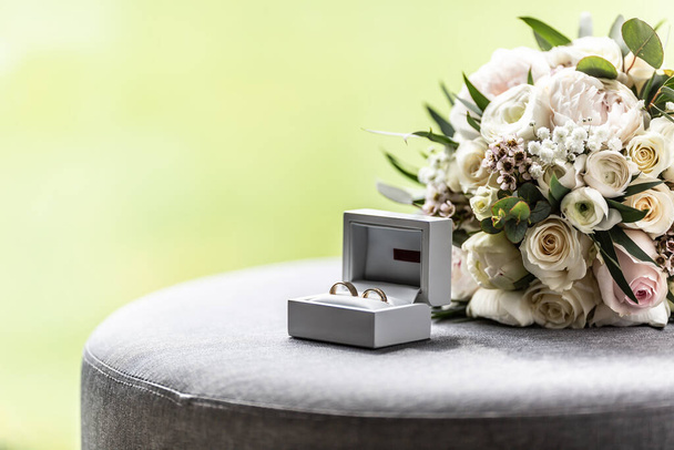 Open box with wedding rings placed next to a bouquette during a wedding. - Foto, Bild