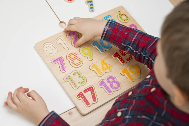 Criança aprendendo números através do jogo. Atividade com números de madeira. Educações em casa, educação pré-escolar, metodologia Montessori. Brinquedo para aprender a contar e estimular a imaginação, criatividade - Foto, Imagem