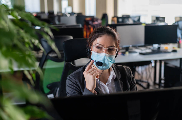 Woman in medical mask at workplace in office.  - Фото, зображення