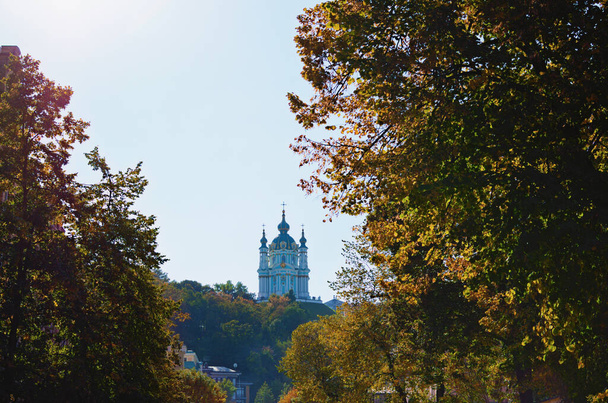 Landschappelijk uitzicht op de oude Sint-Andreas kerk op de top van de heuvel. Boom verlaat de grens. Het is een van de belangrijkste symbolen van Kiev. Mooie zonnige dag. - Foto, afbeelding