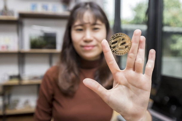 Golden Litecoin (cryptocurrency) in hand of businesswoman. New Virtual money concept - 写真・画像