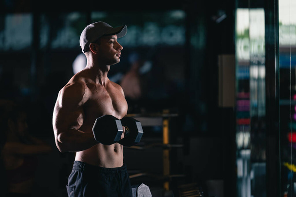 sports foreign man standing are working out with dumbbells in gym and cinematic tone process - 写真・画像