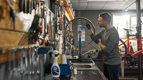 Repairman checking bicycle wheel spoke with key - 写真・画像