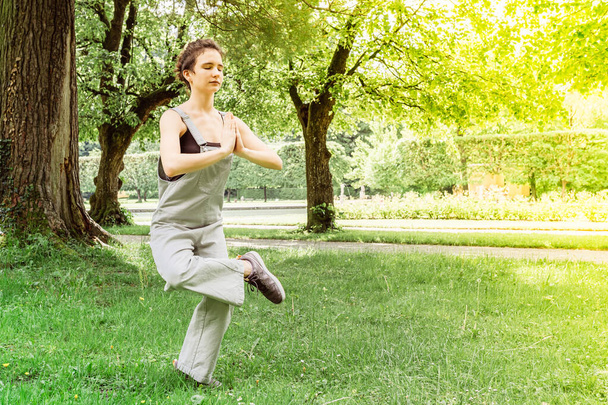 jednota s přírodou v józe pózovat v časném letním ránu nebo večer. Teen dívka cvičit jógu v parku, jóga-natarajasana / Pán tance, vyvažování na jedné noze s rukama v namaste - Fotografie, Obrázek