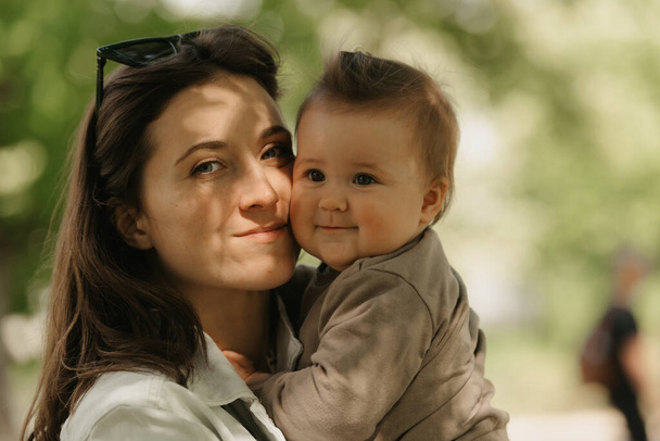 Una giovane madre tiene tra le braccia sua figlia di 7 mesi nel parco. - Foto, immagini