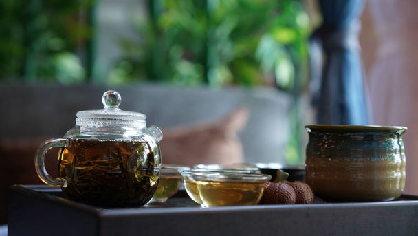 Hagyományos tea szett tálca modern átlátszó pot és tiszta kis csésze hangulatos kínai szobában. Természetes egészséges forró, áttetsző ital szárított levelekkel, jó aromát ad és piát ellazít.. - Fotó, kép