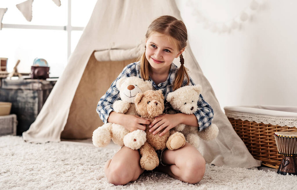 Little girl hugging plush teddies and smiling - Фото, изображение