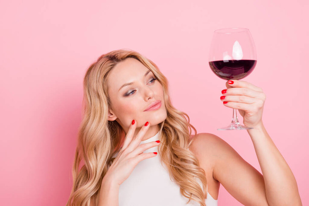 Portrait of pretty lovely girl look interested hold wine glass isolated on pink color background - 写真・画像