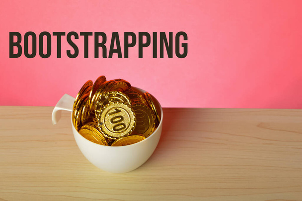 Stack di monete in una tazza con testo BOOTSTRAPPING - Foto, immagini