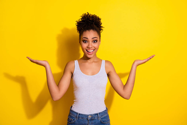 Portrait of amazed excited girl arms palms hold demonstrate empty space proposition isolated on yellow color background - Foto, immagini