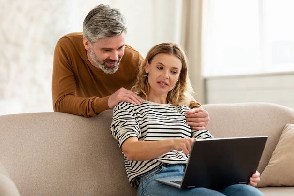 Middle Aged Husband And Wife Using Laptop Browsing Internet Indoor - Photo, Image