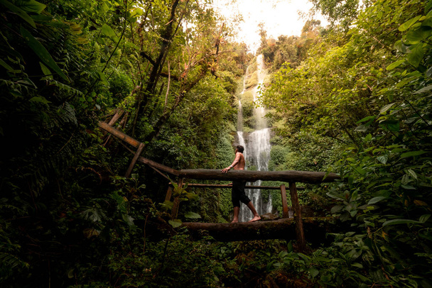 Krajobraz wodospadu z osobą idącą w lewo na drewnianym moście w kolumbijskim regionie kawy - Zdjęcie, obraz
