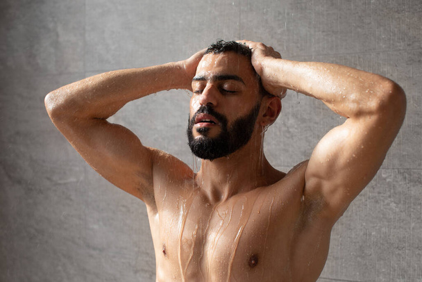 knap jong Arabisch man model het nemen van warm douche - Foto, afbeelding