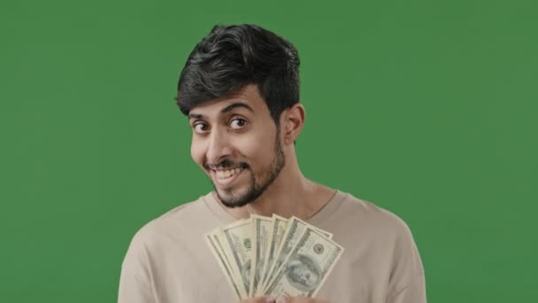 Счастливый арабский человек успешный улыбающийся латиноамериканец индийский бизнесмен изолирован в зеленой студии глядя на камеру держать стопку денег долларов размахивая денежными банкнотами похвастаться выигрыш заработной платы финансовой прибыли сбережения - Кадры, видео