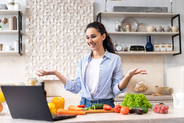 Prepare comida em casa. Senhora latina feliz cozinhar e falar em vídeo chat com a família através do computador portátil - Foto, Imagem