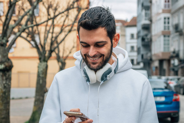 stile urbano giovane uomo a piedi per strada con il telefono cellulare - Foto, immagini