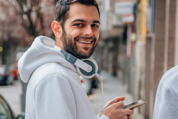 portrait young man with mobile phone and headphones in the city street - Fotoğraf, Görsel