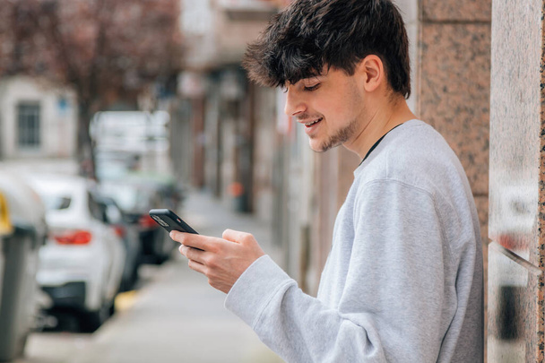 fiatal Y-generációs tini mobiltelefon vagy okostelefon a város utcájában - Fotó, kép