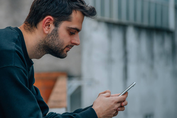 мужчина смотрит на мобильный телефон в руке - Фото, изображение