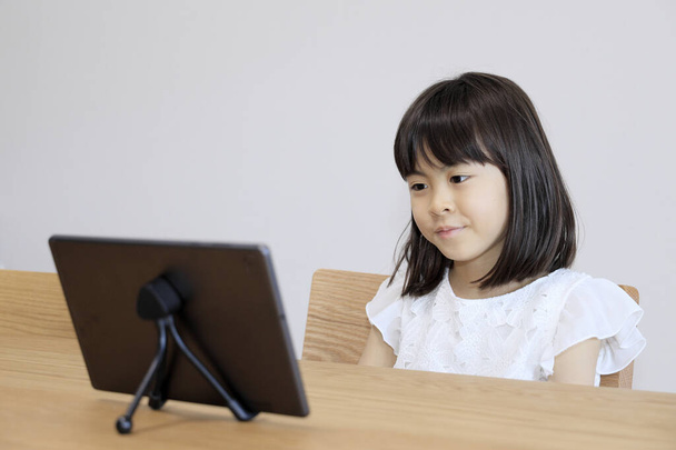 タブレットPCでビデオを見ている日本人女の子(7歳))  - 写真・画像