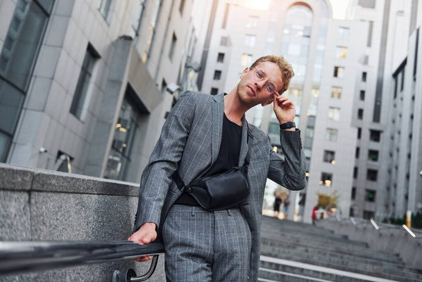Young elegant man in good clothes is outdoors in the city at daytime. - 写真・画像