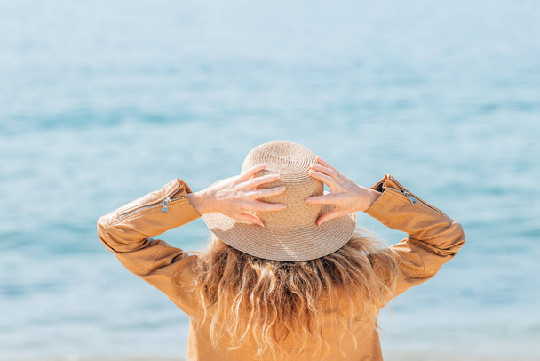 kobieta z kapeluszem na plaży patrząc na morze - Zdjęcie, obraz