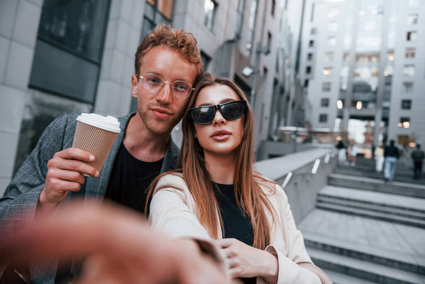 Makes selfie. Woman and man in the town at daytime. Well dressed people. - Фото, изображение