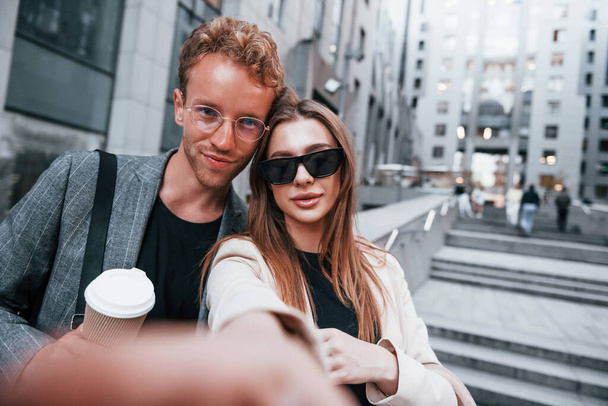 Makes selfie. Woman and man in the town at daytime. Well dressed people. - Photo, image
