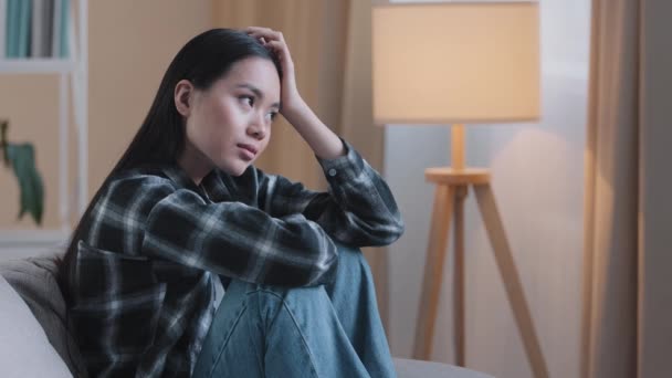Egyedül fáradt unalom szomorú ázsiai nő kimerült lány ül a kanapén otthon érzés boldogtalan szomorúság rossz érzés mentális baj pszichológia baj depressziós kétségbeesett gondolkodó koreai lány gondolja - Felvétel, videó