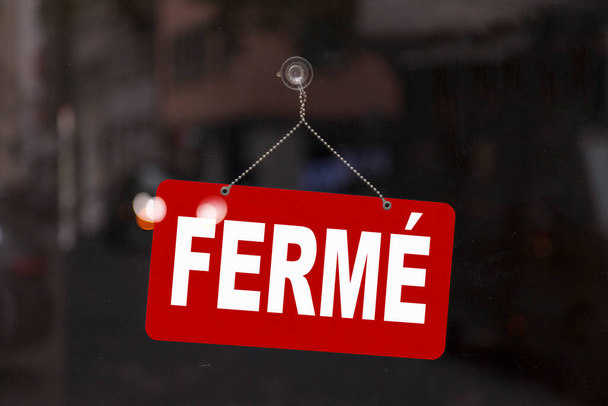 Großaufnahme auf einem roten Schild im Schaufenster eines Geschäfts mit der Botschaft auf Französisch - Ferme - bedeutet auf Englisch - Geschlossen -. - Foto, Bild