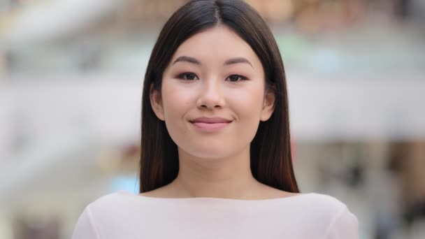 Close up female indoors headshot Asian happy smiling millennial girl. 20s brunette woman model lady with natural make-up face cosmetology service. Businesswoman worker manager client looking at camera - Imágenes, Vídeo