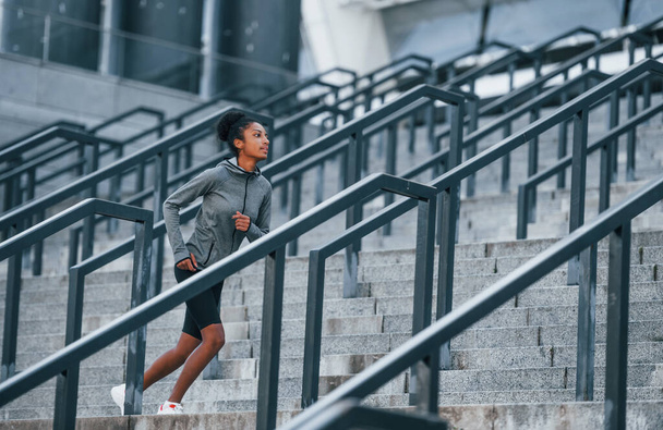 Actieve loper. Jonge Afro-Amerikaanse vrouw in sportieve kleding hebben training buiten op de dag. - Foto, afbeelding
