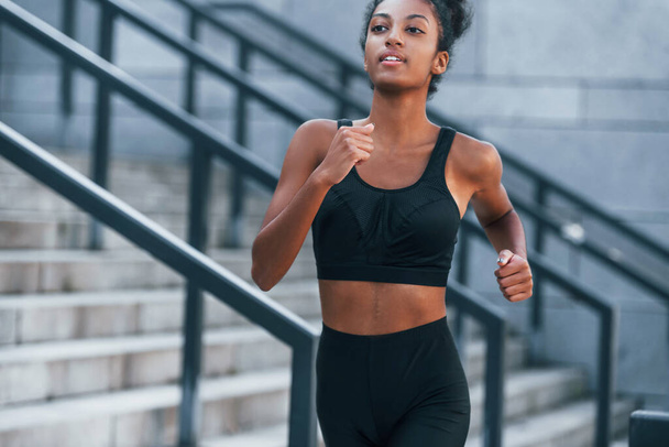 Active runner. Young african american woman in sportive clothes have workout outdoors at daytime. - Foto, Imagen