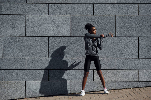 Nuori afrikkalainen amerikkalainen nainen urheiluvaatteissa on harjoitus ulkona päivällä. - Valokuva, kuva
