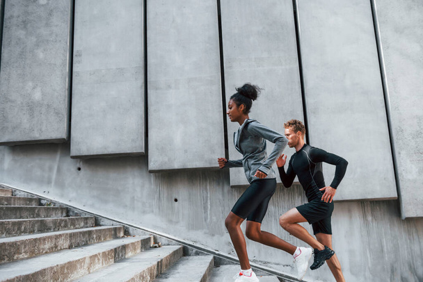 European man and african american woman in sportive clothes have workout together. - Фото, изображение