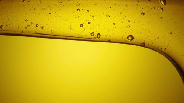 A stream of golden thick honey spills on a yellow background. Sweet honey molasses pours close up. Organic natural honey, syrup or nectar flowing. Sweet dessert, beekeeping product, healthy food. - Photo, Image