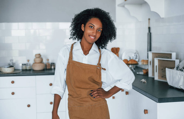 In de keuken. jong Afrikaans amerikaans vrouw met krullend haar binnen thuis. - Foto, afbeelding