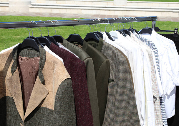 Ceketler, paltolar ve gömlekler ikinci el giyim pazarının açık hava tezgahında satılıyor ama durumu iyi. - Fotoğraf, Görsel