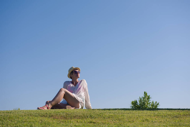 Mujer acostada y leyendo su libro favorito en un prado cubierto de hierba verde fresca en un soleado día de verano o primavera. - Foto, imagen