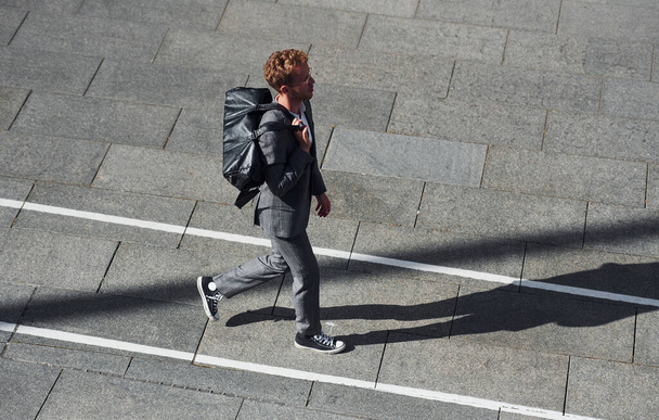 Walks on the road. Young businessman in grey formal wear is outdoors in the city. - Fotografie, Obrázek