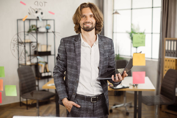Positive manager posing in office with laptop in hands - Foto, Bild