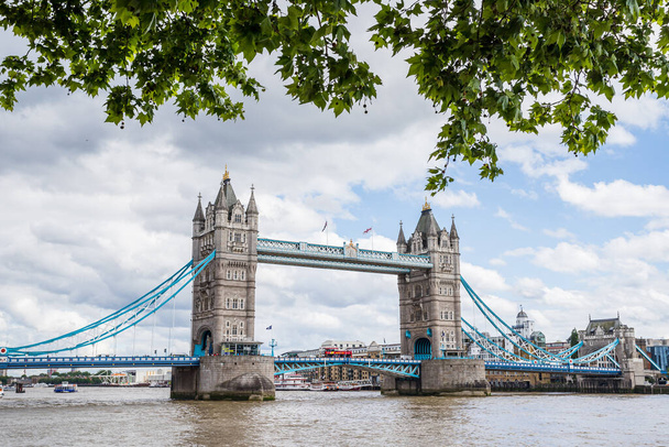 Puente de la Torre que cruza el río Támesis en Londres visto bajo un marco de árboles desde la orilla norte en mayo de 2022. - Foto, imagen