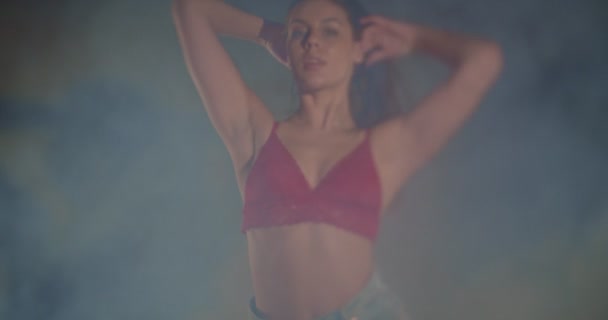 Cool girl in bra and jeans moving seductively, slow motion, shallow depth of field, selective focus, sorrounded by smoke - Footage, Video