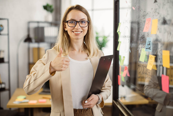 Business lady holding clipboard and smiling at office - Foto, Imagem