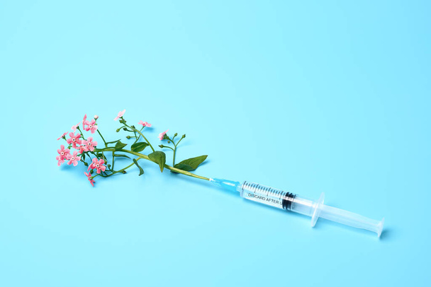 Syringe with pink flowers on blue background, beauty injections creative concept - Φωτογραφία, εικόνα