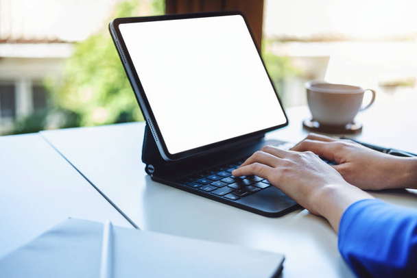 Eine Geschäftsfrau benutzt einen Tablet-Computer mit weißem Bildschirm und Taschenrechner, um Haushaltsdokumente auf seinem Schreibtisch zu berechnen - Foto, Bild
