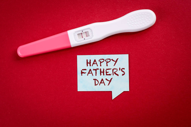 Boldog apák napját. Terhességi teszt és beszédbuborék piros alapon - Fotó, kép
