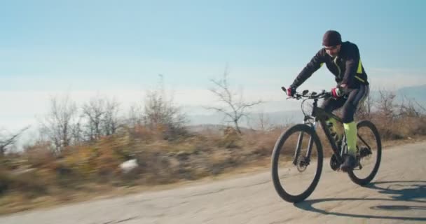 Vanhempi pyöräilijä ratsastaa tiellä kukkuloilla - Materiaali, video
