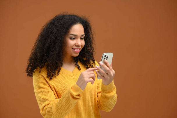Attractive young multiracial woman web browsing on smartphone, millennial female chatting on social networks, using mobile app, texting online with friends, sharing news - Valokuva, kuva